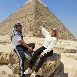 Guia local egípcio explicando a história das Pirâmides de Gizé a turistas brasileiros durante passeio no Egito"